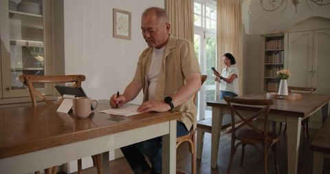 Asian Couple Working Together in Cozy Dining Room in Sunlight