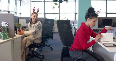 Multiracial female coworkers celebrating holiday, exchanging gifts and planning together