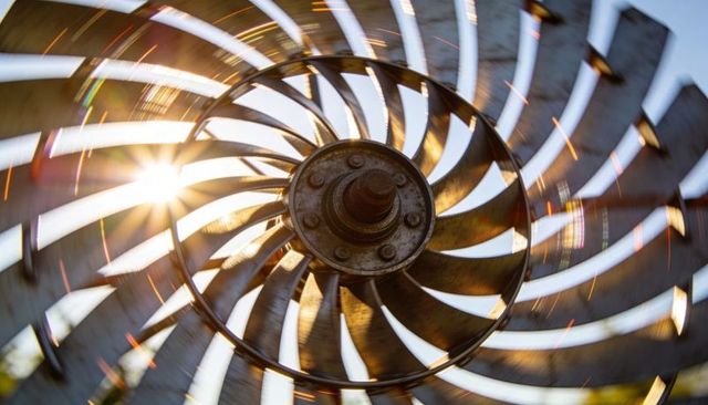 Spinning turbine rotor with spiral vanes and sun flare, radial motion blur, industrial art