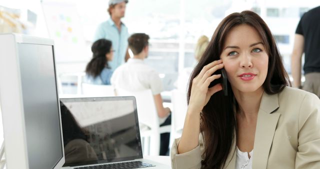 Woman working at her desk talking on the phone in creative office