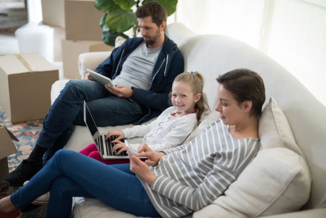 Parents and daughter using electronic devices at home