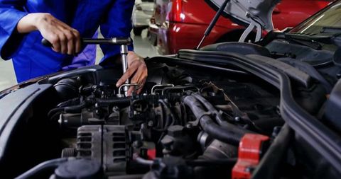 Female Mechanic Tightening Engine with Socket Wrench in Auto Repair Workshop Close-Up