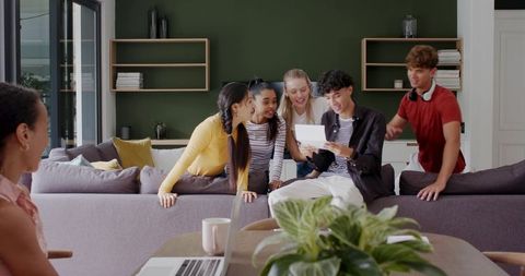 Diverse friends gathering around sofa, reading letter and celebrating in modern lounge