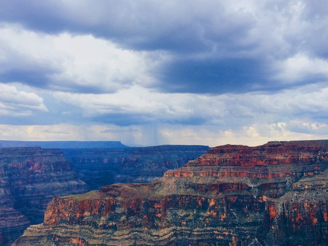 Capturing a dramatic scene of storm clouds hovering over the Grand Canyon at sunset. The rugged cliffs and steep valleys showcase the natural beauty and geological grandeur of this iconic landmark. Perfect for use in travel brochures, nature documentaries, educational materials, and inspirational posters.
