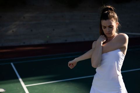 Female tennis player stretching on court during practice
