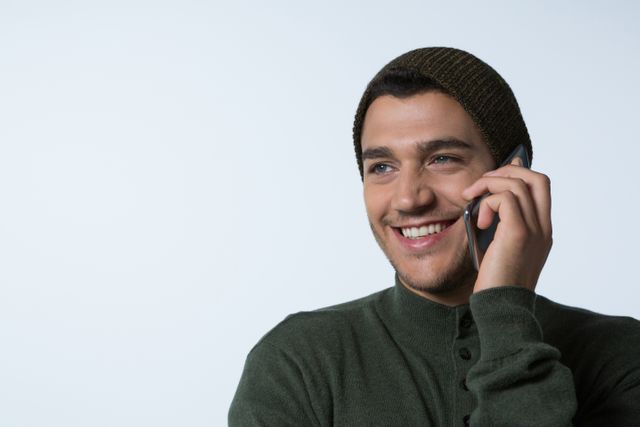 Man in winter cloth talking on mobile phone against white background