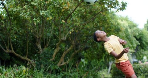 African american teen heading soccer ball in park during outdoor summer play