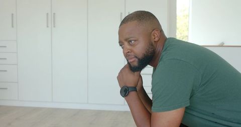 African american man sitting and contemplating in minimalist interior with natural light