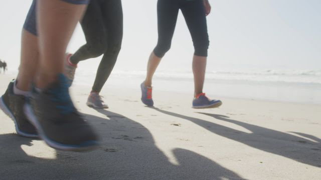 Women exercising together along a sunny beach, emphasizing fitness and camaraderie are seen running in dynamic motion. Useful for promoting health and wellness programs, outdoor activities, or articles discussing group fitness benefits.