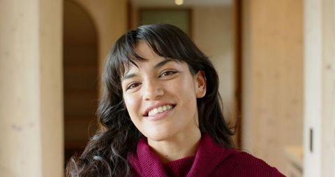 Smiling Woman in Burgundy Sweater in Warm Wood-paneled Hallway