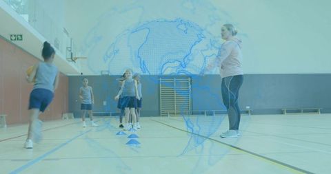 Youth basketball training session with coach guiding cone drill in school gymnasium