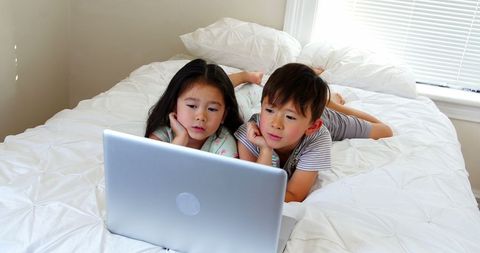 Kids Engaged Learning on Laptop in Cozy Bedroom