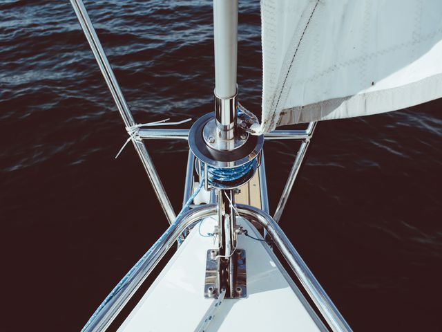 Captured from above, showing the bow and mast of a sailing boat on calm water. Ideal for illustrating nautical themes, boat maintenance articles, or promoting sailing activities. Great use in travel brochures, adventure blogs, and outdoor recreation materials.