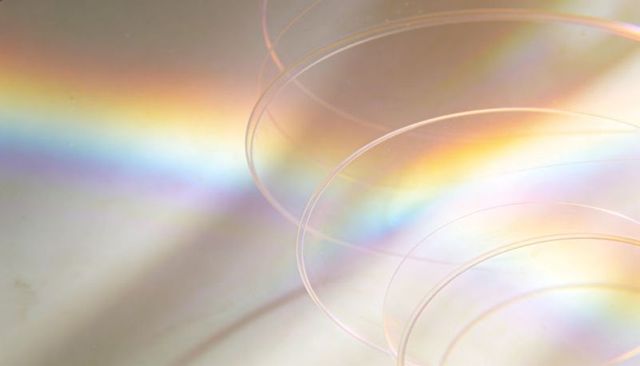 Macro iridescent spiral prism rings on reflective surface with soft rainbow gradient light