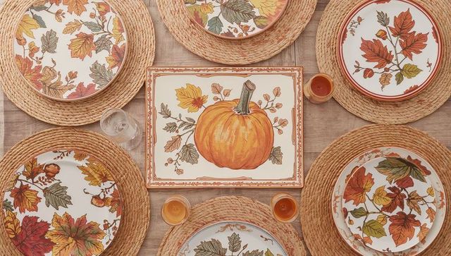 Autumn pumpkin centerpiece with leaf pattern dinnerware on rustic woven placemats