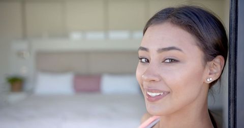 Smiling Woman Earnestly Engaging Camera in Bedroom