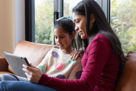 Indian mother and daughter bonding while learning on tablet at home