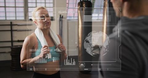 Female athlete taking break with towel viewing ar fitness data in boxing studio