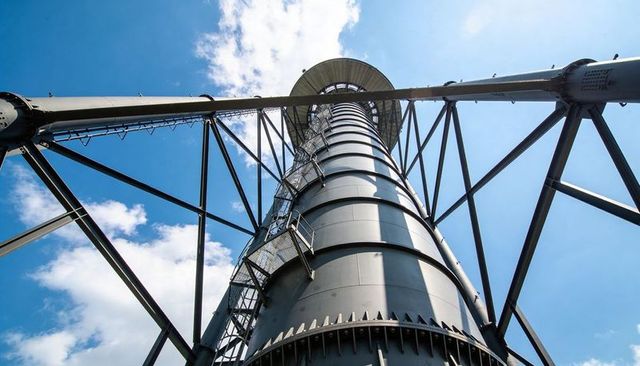 Upward view of industrial steel observation tower with spiral staircase and truss support