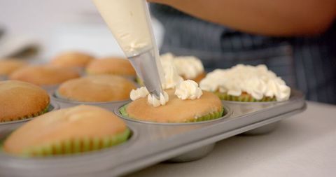 Pastry Chef Decorates Cupcakes with Creamy Frosting in Kitchen