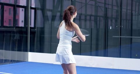 Female Athlete Swinging Padel Racket on Modern Blue Court
