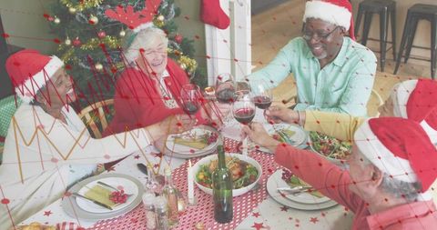 Seniors celebrating holiday dinner toasting wine around festive table with Christmas tree