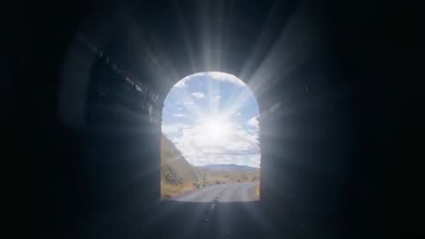 Sunburst through Tunnel Archway Illuminating Desert Road at Exit with Dramatic Light Rays