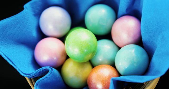 Collection of colorful spherical candies resting in a basket decorated with blue fabric. Perfect visuals for candy shops, advertisements, or packaging design. Brings a sense of joy and vibrancy to any project related to sweets and treats.