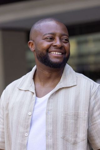 Smiling african man looking left wearing beige shirt and white tee urban pro headshot