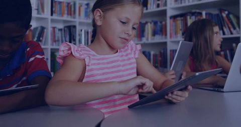 Elementary girl using tablet in school library for digital learning and collaboration