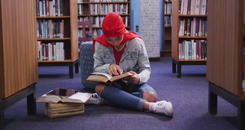 Asian Female Student Reading in Library with Red Hijab