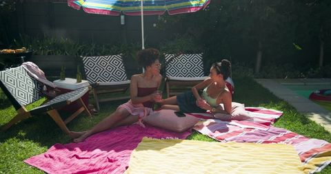 Diverse friends chatting and relaxing near pool on sunny day
