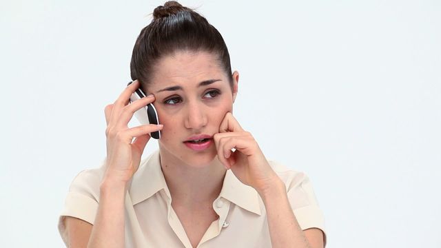 Young woman engaged in a serious phone call. Ideal for themes related to communication, business discussions, stressful situations, mental health, customer support, problem solving, or conveying anxiety in professional or personal contexts.