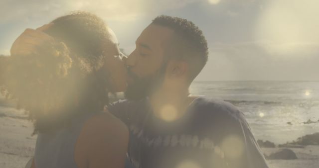 Image of lens flares over diverse couple embracing and kissing on beach against sea and sky. Digital composite, multiple exposure, love, togetherness, happiness, vacation and romance concept.