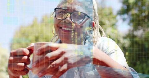 Smiling senior woman holding mug outdoors with digital binary overlay and warm light