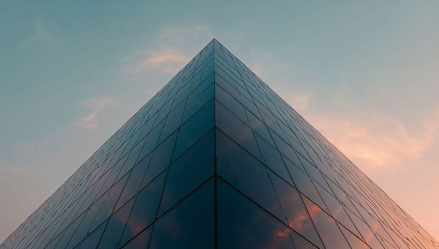 Glass apex skyscraper reflecting sunset sky emphasizing symmetry and geometric perspective