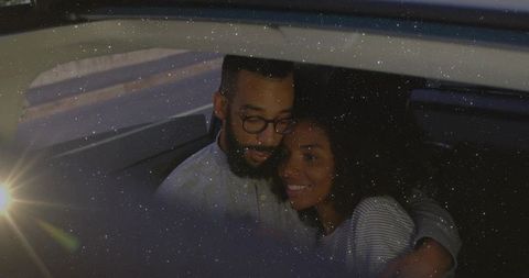Couple embracing in backseat at night with soft light
