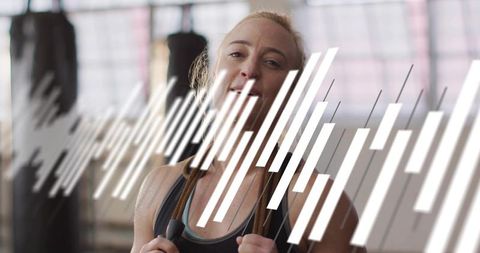 Smiling fit woman jumping rope in industrial gym, sweating during cardio workout