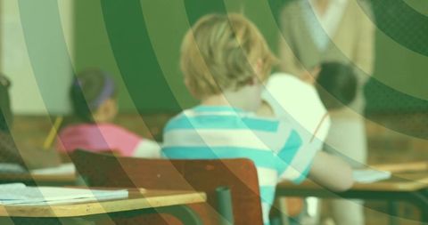Child writing at desk wearing striped shirt in classroom with green overlay design