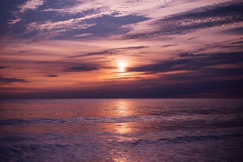 Violet Sunset Over Calm Ocean Reflecting Golden Light Across Serene Sea