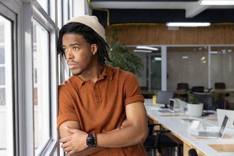 Contemplating african american man leaning on windowsill in modern coworking office