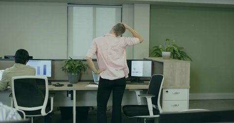 Female office worker in pink shirt using computers in modern workspace