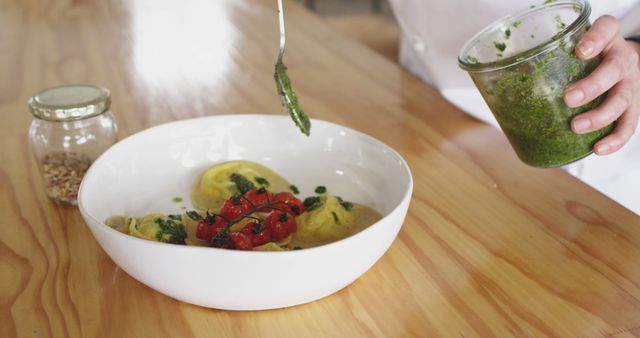 Chef Garnishing Pasta with Fresh Green Pesto Sauce in a White Bowl - Download Free Stock Images Pikwizard.com