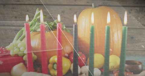 Glowing taper candles framing autumn harvest centerpiece pumpkins gourds rustic wood