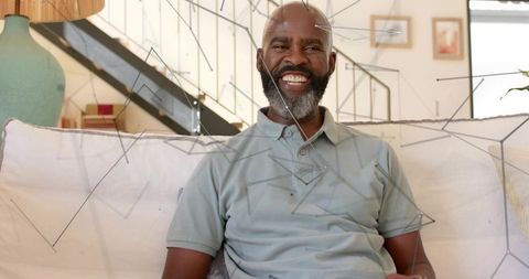 Senior man smiling on sofa in sunlit contemporary living room with geometric wire overlay