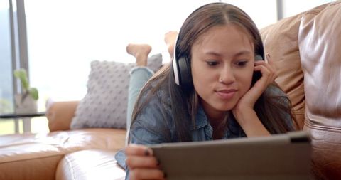 Young Woman Relaxing with a Tablet and Headphones on Sofa