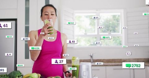 Woman drinking green smoothie in kitchen surrounded by social media engagement overlays