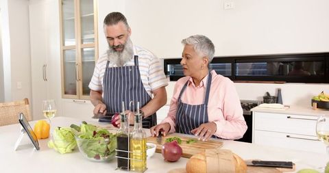 Mature couple cooking healthy mediterranean salad together