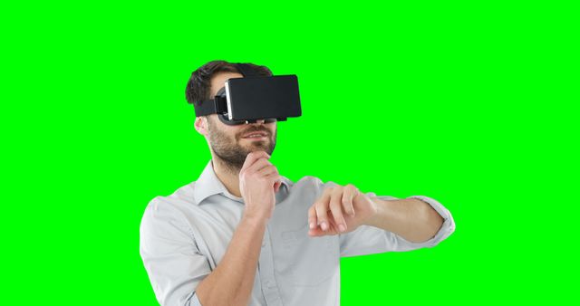 Man wearing a virtual reality headset experiencing immersive digital technology against green screen background. Useful for visualizing futuristic concepts, promotional materials for VR technology and immersive experiences, and educational content on innovative tech.