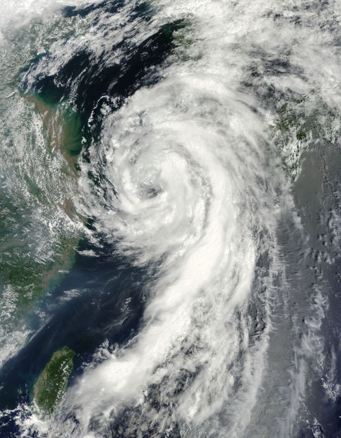 This striking image shows Tropical Storm Dianmu swirling over the East China Sea on August 10, 2010, as captured by the MODIS instrument on NASA’s Terra satellite. The storm exhibits a well-defined eye and spiral cloud bands extending hundreds of kilometers southward. This image could be used in educational materials about severe weather and meteorology, presentations on climate science, or news articles covering historic weather events.
